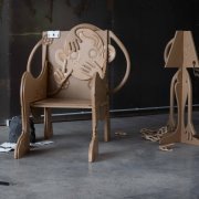 Installation eines geschnitzten Stuhls, Lampe, Spielzeugauto, Papier, und Trümmer 