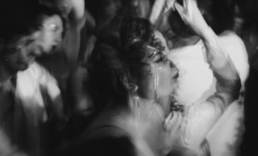 Black and white photo of people dancing. The picture is out of focus in exception of the woman in the center of the photo.