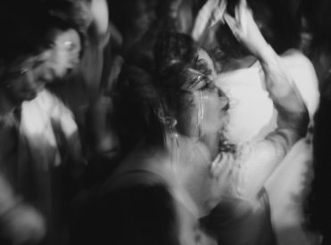 Image en noir et blanc de personnes dansant. L'image est floue, à l'exception d'une femme.