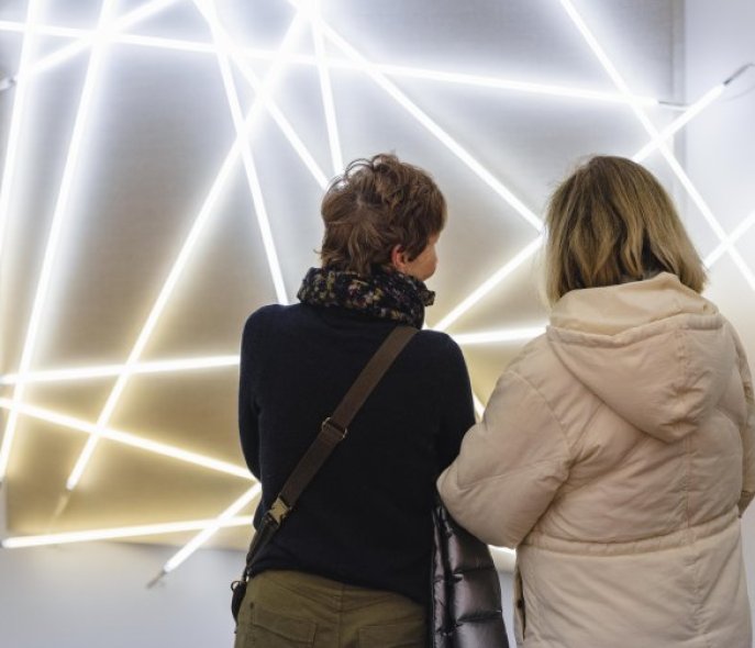 Two female visitors in front of an artwork made of neon tubes