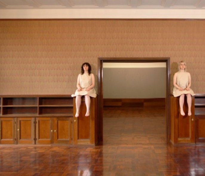 Two women are sitting on dressers next to a door