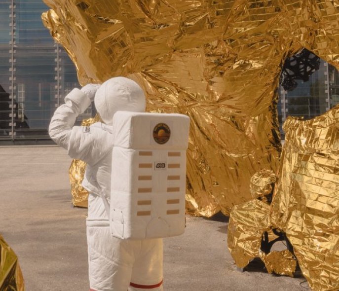 An astronaut in front of a sheet of gold foil