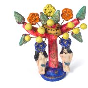 Auf einem roten Baum mit dickem Stamm und zwei dicken Ästen, an denen grosse grüne Blätter und gelbe Früchte und gelbe, orange und blaue Blüten hängen, liegt eine orange Schlange mit schwarzen Punkten. Darunter stehen zwei Figuren, eine Frau und ein Mann, beide mit langen schwarzen Haaren.