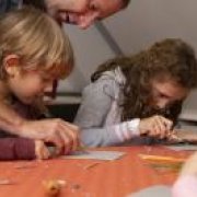 Kinder beim Arbeiten mit Linoleum Ein Junge und ein Mädchen bearbeiten mit Schnitzwerkzeug Linoleumplatten an einem Tisch