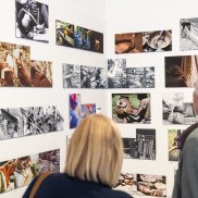Fotowand in der Ausstellung "Schöpfer*innen" Fotowand in der Ausstellung "Schöpfer*innen". Davor stehen eine Frau und ein Mann.