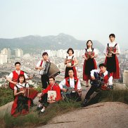 Volksmusiker*innen auf einem Hügel stehend, im Hintergrund den Blick auf eine Grossstadt