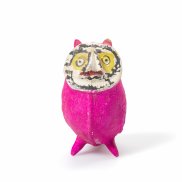 Eine kleine pinke Figur mit bemaltem Gesicht steht vor hellem Hintergrund. Sie wirkt wie eine handgemachte Kunst- oder Spielzeugfigur.