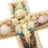 Kreuz mit weisslicher Jesusfigur in der MItte, darum herum sind verschieden grosse und farbige Muscheln drapiert.