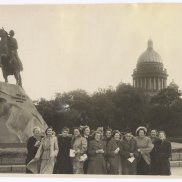 Die Schwarzweissfotografie von 1953 zeigt Helene Bosserts Reisegruppe in St. Petersburg. Die Gruppe von Frauen in Mänteln steht neben dem ehernen Reiter, dem Denkmal für Zar Peter den Ersten; im Hintergrund sieht man Bäume und einen Kuppelbau.