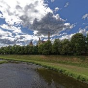 im Vordergrund die Murg, dahinter Bäume, Wasserturm und Brauereigebäude, Wolken