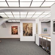 Blick in den Ausstellungsraum mit verschiedenen Gemälden und Fotografien
