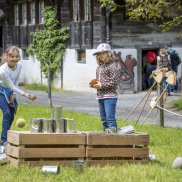 Annual theme 2023 at the Swiss Open-Air Museum: Let's play! Children throwing cans at the Ballenberg Open-Air Museum.