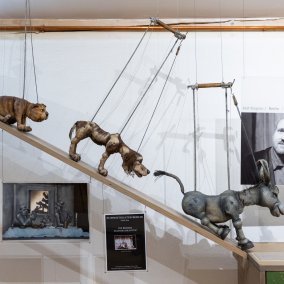 Several dolls walk down a flight of stairs