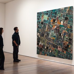 Deux visiteurs se tiennent devant une œuvre d'art de Carl Cheng