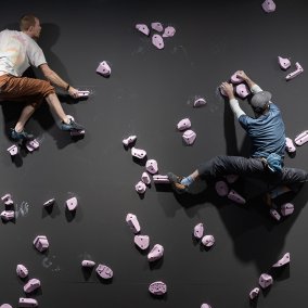 Das Bild zeigt das Kunstwerk "Free Solo" des Künstlerduos Özlem Günyol und Mustafa Kunt. Zu sehen ist eine Kletterwand mit mehreren Personen. 