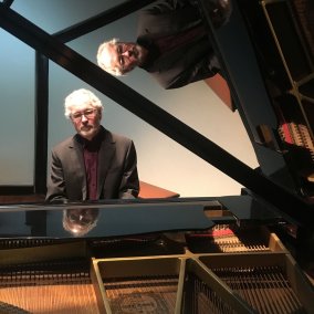 Der Pianist William Cuthbertson sitzt vor einem Piano. 