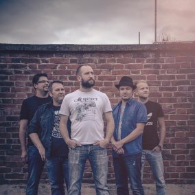 Die Band EAT THE BEAT steht vor einer Mauer. 