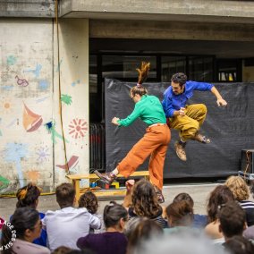Tänzer*in in blau, grün, oranger und gelber Kleidung