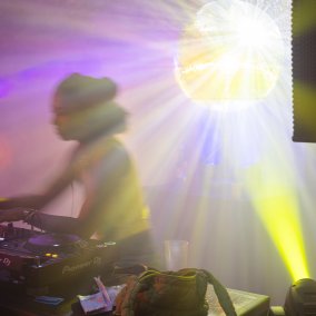 Djane im Licht einer glitzernd, strahlenden Discokugel Djane im Licht einer glitzernd, strahlenden Discokugel