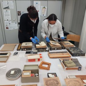 Blick hinter die Kulissen bei der Beforschung der Fotosammlung; zwei Forscherinnen begutachten Fotoalben