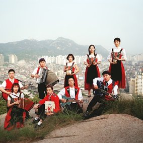 Volksmusiker*innen auf einem Hügel stehend, im Hintergrund den Blick auf eine Grossstadt