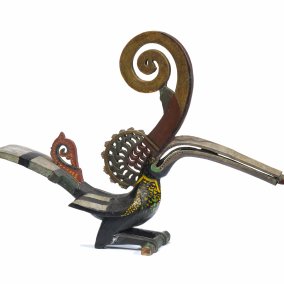 Bird figurine in shades of gold and red with a very long beak and long, curved horn.