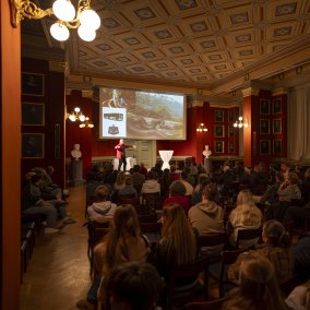 Vortrag in der Aula mit Präsentation auf der Leinwand (c) Jeton Shali