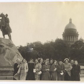 Die Schwarzweissfotografie von 1953 zeigt Helene Bosserts Reisegruppe in St. Petersburg. Die Gruppe von Frauen in Mänteln steht neben dem ehernen Reiter, dem Denkmal für Zar Peter den Ersten; im Hintergrund sieht man Bäume und einen Kuppelbau.