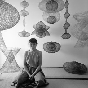 Portrait of Japanese American artist Ruth Asawa as she kneels on the floor amid several of her looped-wire sculptures, November 1954. Photo: Nat Farbman/The LIFE Picture Collection/Shutterstock Artwork © 2025 Ruth Asawa Lanier, Inc., Courtesy David Zwirner