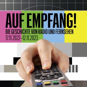 Eine Hand hält eine Fernbedienung, darüber ist der Ausstellungstitel zu sehen.