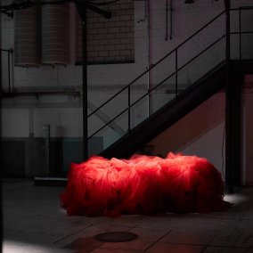 Ein rotes Objekt in einer dunklen Umgebung, Treppen im Hintergrund.