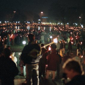 Man sieht eine Menschenkette im Dunklen. Die Menschen halten Lichter in den Händen.