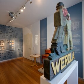 Blick auf Wandtexte und Exponate sowie ein Schild der Werola im Jüdischen Dokumentationsraum