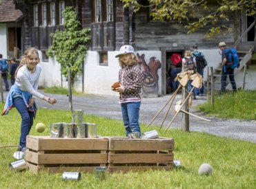 Des enfants lancent des canettes au musée suisse en plein air Ballenberg.