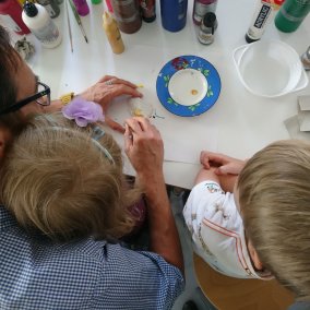Familiensonntag Vater mit zwei Söhnen beim Bemalen einer Figur