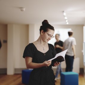 Eine Besucherin des Salmen ist in einem Ausstellungsraum und schaut ein Buch an