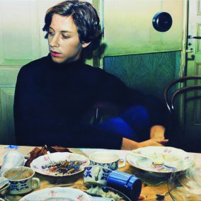 A man is sitting at a table with used dishes and leftover food