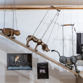 Several dolls walk down a flight of stairs