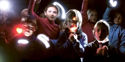 Das Bild zeigt eine Gruppe Kinder mit Taschenlampen in der Nacht.