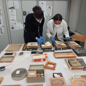 Blick hinter die Kulissen bei der Beforschung der Fotosammlung; zwei Forscherinnen begutachten Fotoalben