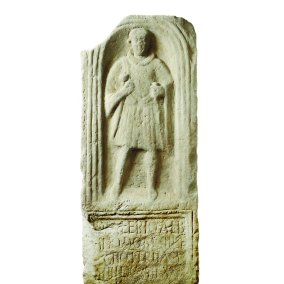 eine Steinplatte mit einem Relief von einem Mann und teilweise leserlicher Schrift