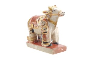 Angelehnt an eine Kuhh aus Marmor mit gold-rotem Geschirr wie bei einem Pferd sitzen und stehen zwei Personen, auch in Gold-Rot gekleidet