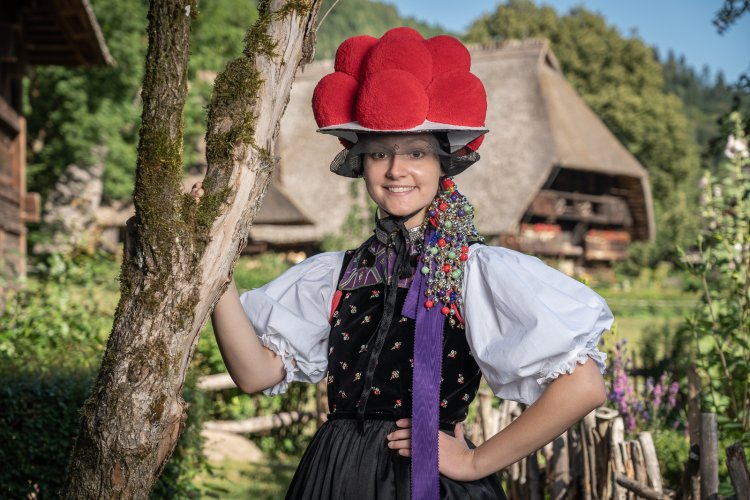 Girl with the traditonal costume of Gutach with the Vogtsbauernhof in the background
