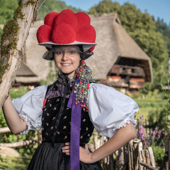 Porteuse de costume traditionnel avec le Vogtsbauernhof en arrière-plan