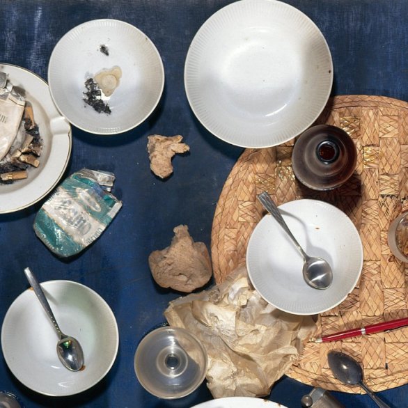 Auf der Abblindung sieht man ein Stillleben vom Künstler  Daniel Spoerri. Es zeigt von oben als Traufsicht scheinbar einen Tisch. Man erkennt diesen aber nicht. Die Fläche ist mit einem dunkelblauen Tuch bedeckt. Darauf befinden sich viele Gegenstände weiße, kleine Schalen, Teelöffel, Gläser. In einer Schüssel befinden sich viele Zigarettenstummel. Es liegen zwei leere, Zigarettenschachtel auf dem Tisch. Alles sieht aus, als wären die Menschen gerade vom Tisch aufgestanden und hätten alles so zurück gelasse