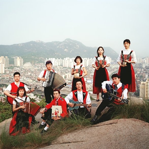 Volksmusiker*innen auf einem Hügel stehend, im Hintergrund den Blick auf eine Grossstadt