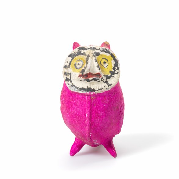 Eine kleine pinke Figur mit bemaltem Gesicht steht vor hellem Hintergrund. Sie wirkt wie eine handgemachte Kunst- oder Spielzeugfigur.