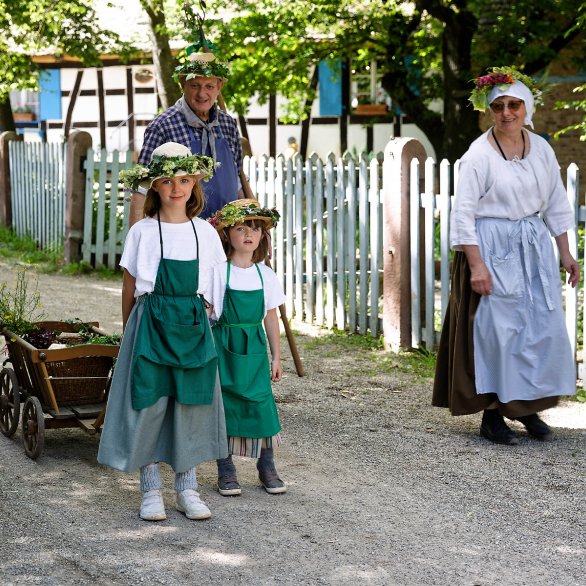 Famille paysanne alsacienne déambulant avec un wagala et des couronnes de fleurs