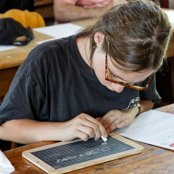 Une élève s'applique pour écrire sur son ardoise la bonne réponse