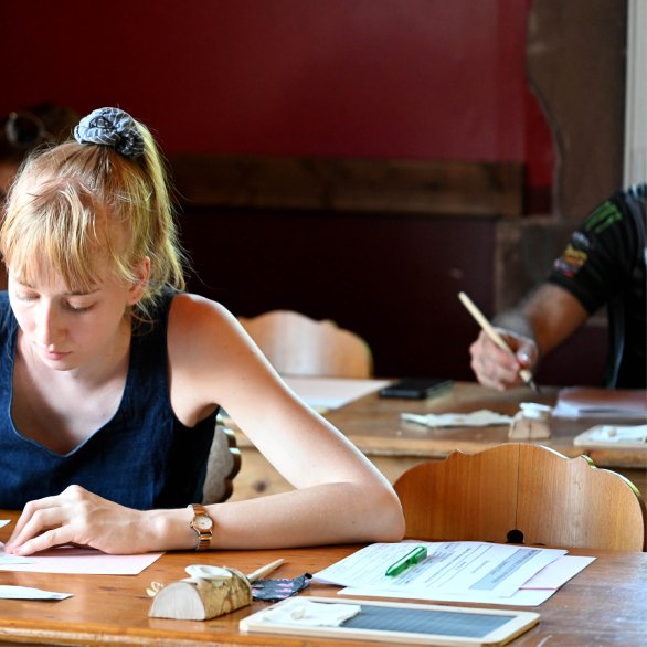 Les écoliers sont concentrés sur leurs devoirs, plume à la main.